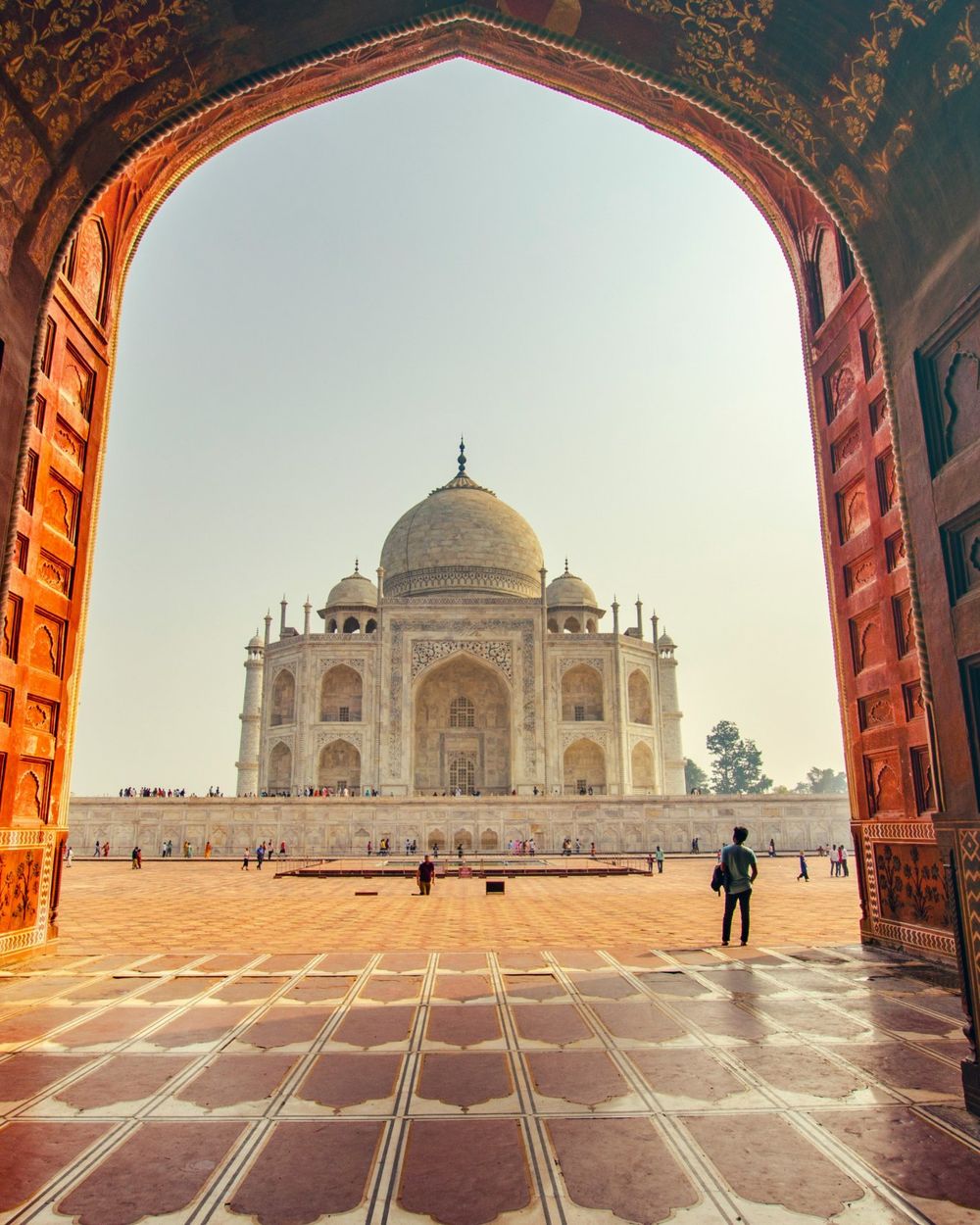 The Taj Mahal seen through a carved red sandstone archway